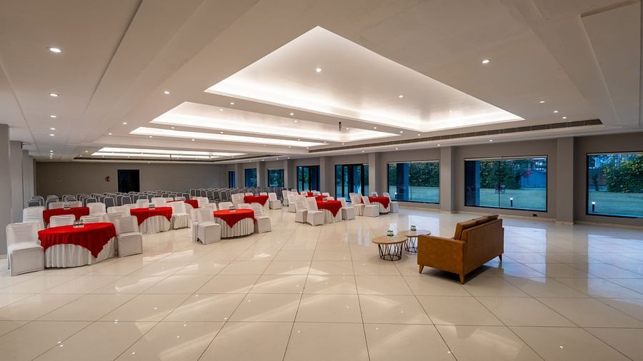 Side view of tables with neatly decorated tablecloths, a plush sofa, and two round tables set in front at DLS Forest Vines Resort.